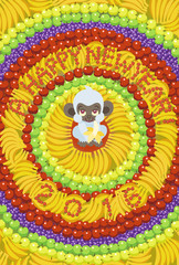 曼陀羅のように果物を並べた中心で、バナナを食べる白い猿（2016年の年賀状／はがき縦）