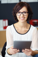 lächelnde geschäftsfrau mit brille hält tablet-pc in der hand