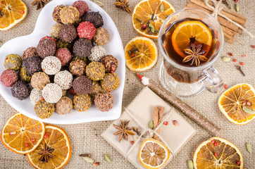 Handmade chocolate candies collection, dried oranges, spices, mulled wine, wooden pencil on wooden background. Christmas, New Year and winter.