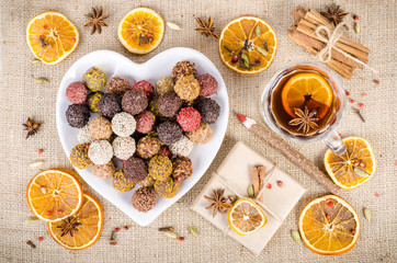 Handmade chocolate candies collection, dried oranges, spices, mulled wine, wooden pencil on wooden background. Christmas, New Year and winter.