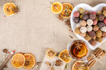 Handmade chocolate candies collection, dried oranges, spices, mulled wine, wooden pencil on wooden background. Christmas, New Year and winter. Free space for your text.
