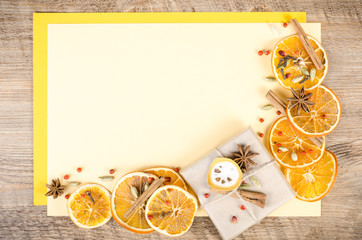 Dried oranges, cinnamon, cloves, cardamom, handmade milk chocolate in rustic packing, mulled wine on yellow and wooden background. Christmas, New Year and winter. Free space for your text.