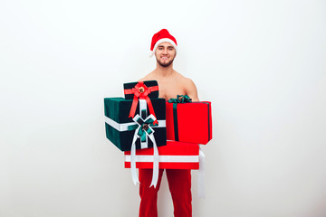 Handsome bearded guy with a naked body dressed as Santa Claus holding gifts.