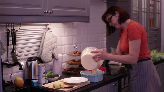 A woman pours the batter in the baking form