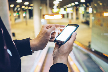 Side view of young businessman using modern smart phone with blank screen