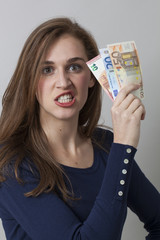 value for money concept - furious 20s woman holding Euro bills for claiming earnings or economic frustration,studio shot