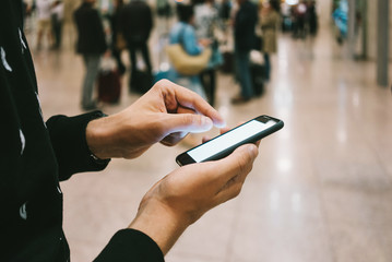 Young businessman using modern smartphone with blank screen at the airport