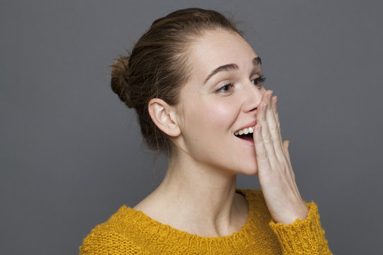 glowing happiness concept - surprised 20s girl smiling for wellbeing and serenity,studio shot on gray background