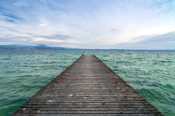 Obraz na płótnie Canvas wooden pier and cloudy sky over Garda lake - Italy