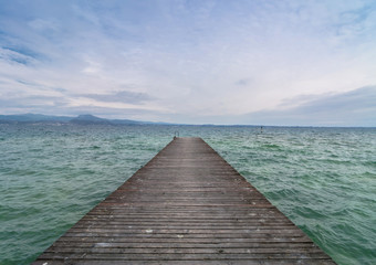 Fototapeta premium drewniane molo i pochmurne niebo nad jeziorem Garda - Włochy
