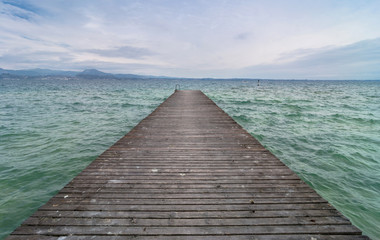 wooden pier and cloudy sky over Garda lake - Italy