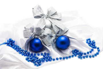 Blue and silver Christmas balls with bows  on white satin fabric