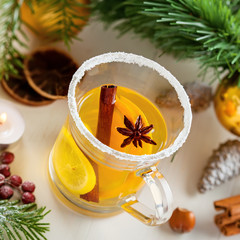 Glass of mulled cider by Christmas tree with decorations. Traditional hot drink. Top view.