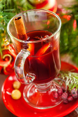 Glass of mulled wine by Christmas tree with decorations. Delicious drink for party.