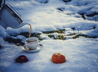 Cup of tea and apples on snow.