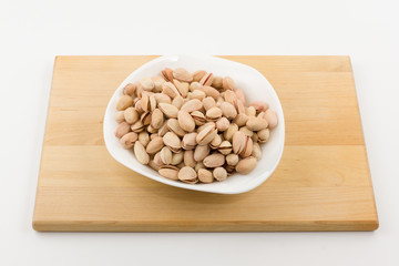 plateful of pistachios costs on a plate on a white background