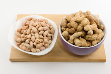 platefuls of different nuts stand on a plate on a white backgrou