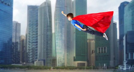 boy in red superhero cape and mask flying on air