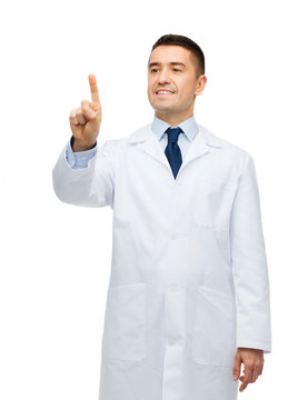 Smiling Male Doctor In White Coat Pointing Finger