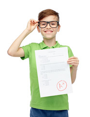 happy boy in eyeglasses holding school test result