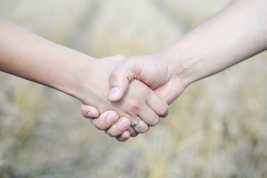 Male and female holding hands outdoors over bokeh background