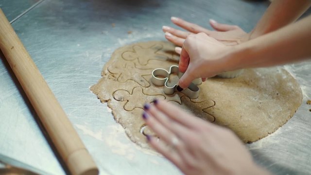 The hands are cutting gingers boys out of the dough