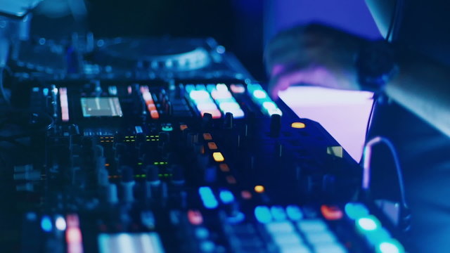 DJ mixing tracks on console at dance music party