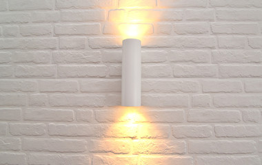 The wall lamp with illumination on a white brick wall