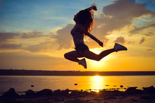 Image of beautiful young lady having fun jumping high over open water on summer outdoors copy space background