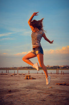 Image of beautiful active young lady having fun jumping high over open water on summer outdoors background copy space