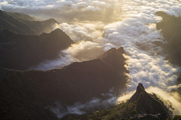 Steile Berggipfel und Felsen über dem Morgennebel im Tal beim Sonnenaufgang über Madeira und dem Gipfel des Pico do Arieiro