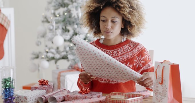 Happy young African woman wrapping presents