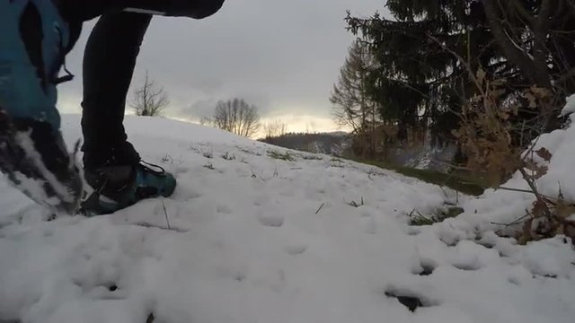 Man walking down the hill in snow at sunset