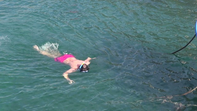 Teenager with pink swimming trunks snorkeling in the ocean