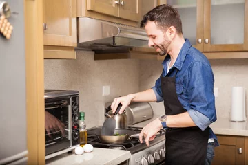 Crédence de cuisine en verre imprimé Cuisinier Man cooking breakfast at home