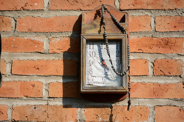 Reloj y rosario decoran la pared de ladrillos.