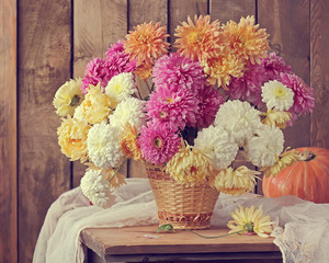 Still life with a bouquet of chrysanthemums in a basket and pump