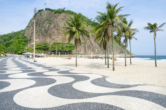 Scenic karst mountain landscape with iconic sidewalk tile pattern at the Leme end of Copacabana Beach in Rio de Janeiro, Brazil 