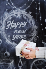 Woman hands holding wrapped gift box on Happy New Year background