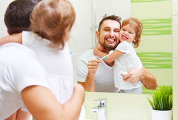 Fototapeta premium Happy family father and child girl brushing her teeth in bathroo