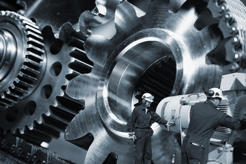 two mechanics working with large cogwheels and gears machinery