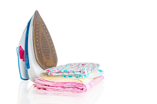 Steam iron with clean clothes on white background