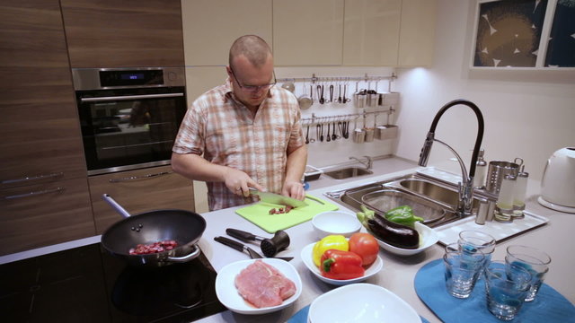 Man cuts the sausages on the Board and lay in pan