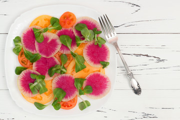 Colorful and healthy carpaccio salad with watermelon radish, tomato and corn salad. Top view, free text copy space
