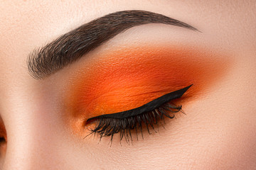 Close-up of woman eye with beautiful orange smokey eyes with bla - obrazy, fototapety, plakaty