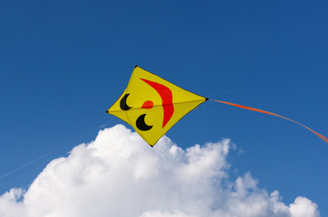Yellow kite with smiling face isolated on blue sky