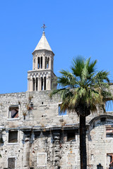 Fototapeta na wymiar Saint Domnius bell tower behind ancient wall and a palm tree. In Split, Croatia. Split is famous touristic destination and UNESCO World Heritage Site.