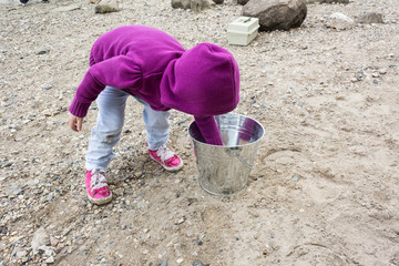 little girl bending down playing with rocks