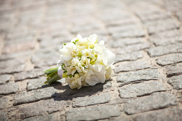 Fototapeta na wymiar Bride's bouquet on paved road