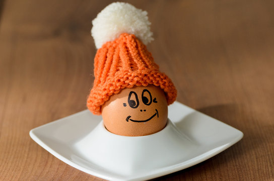 Smiling egg with knitted bonnet sitting in white eggcup